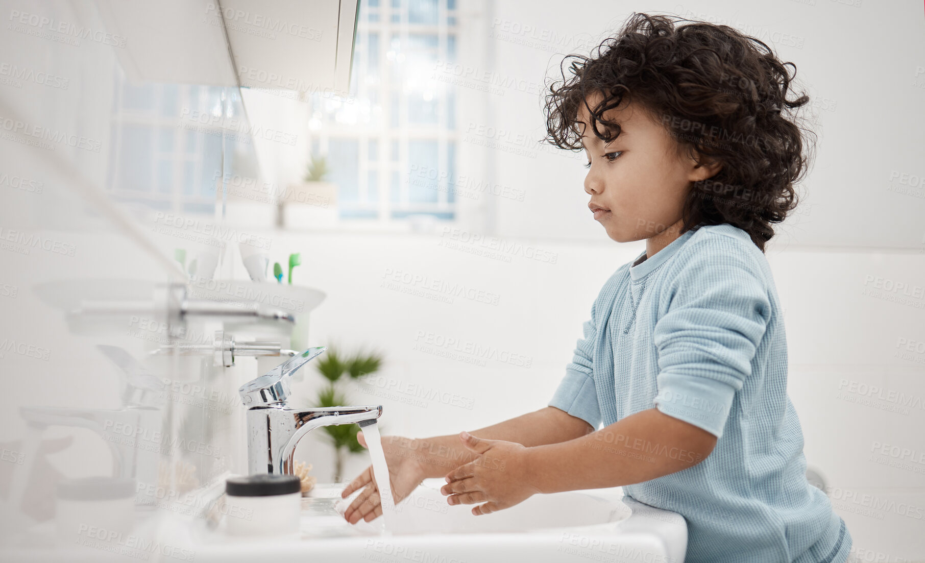 Buy stock photo Shot of an adorable little boy washing his hands at a tap in a bathroom at home