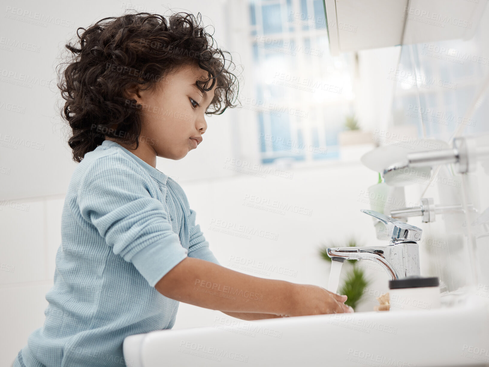 Buy stock photo Shot of an adorable little boy washing his hands at a tap in a bathroom at home