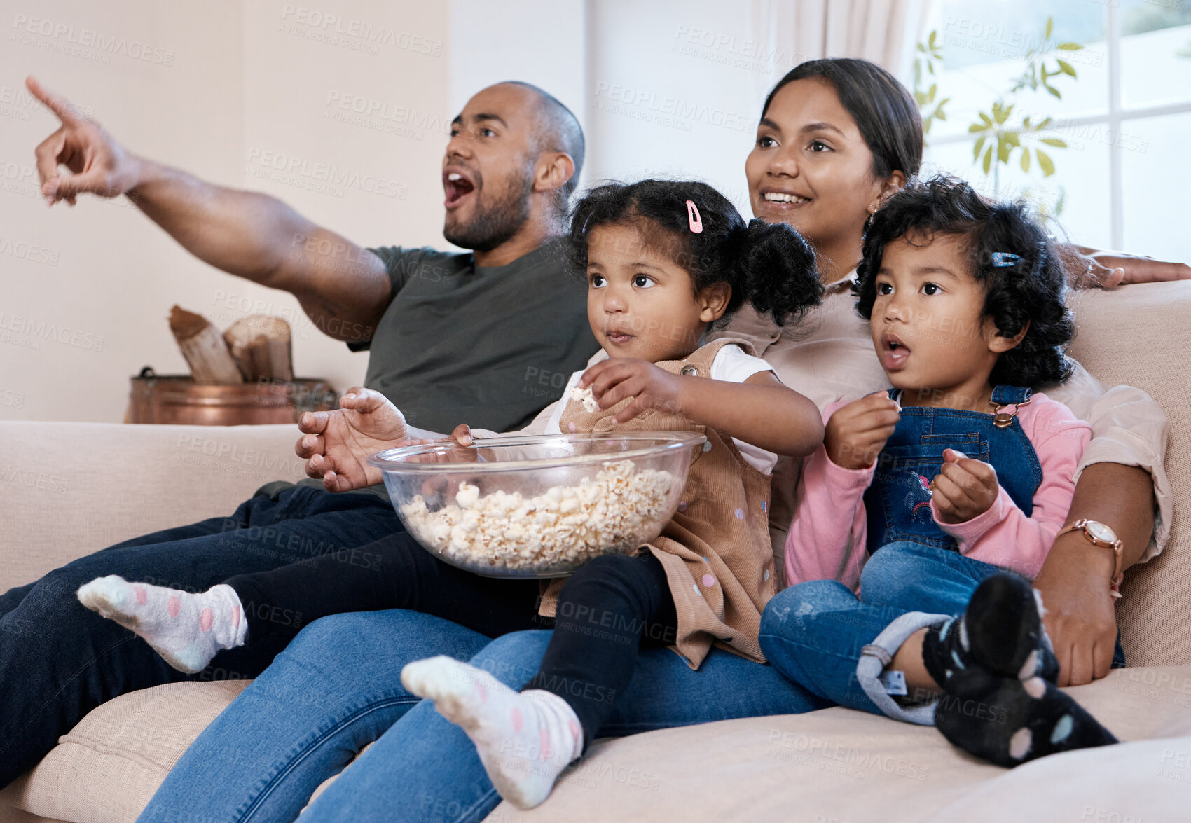 Buy stock photo Shot of a happy family eating popcorn while watching television together at home