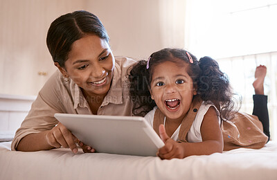 Buy stock photo Shot of a little girl using a digital tablet with her mother at home