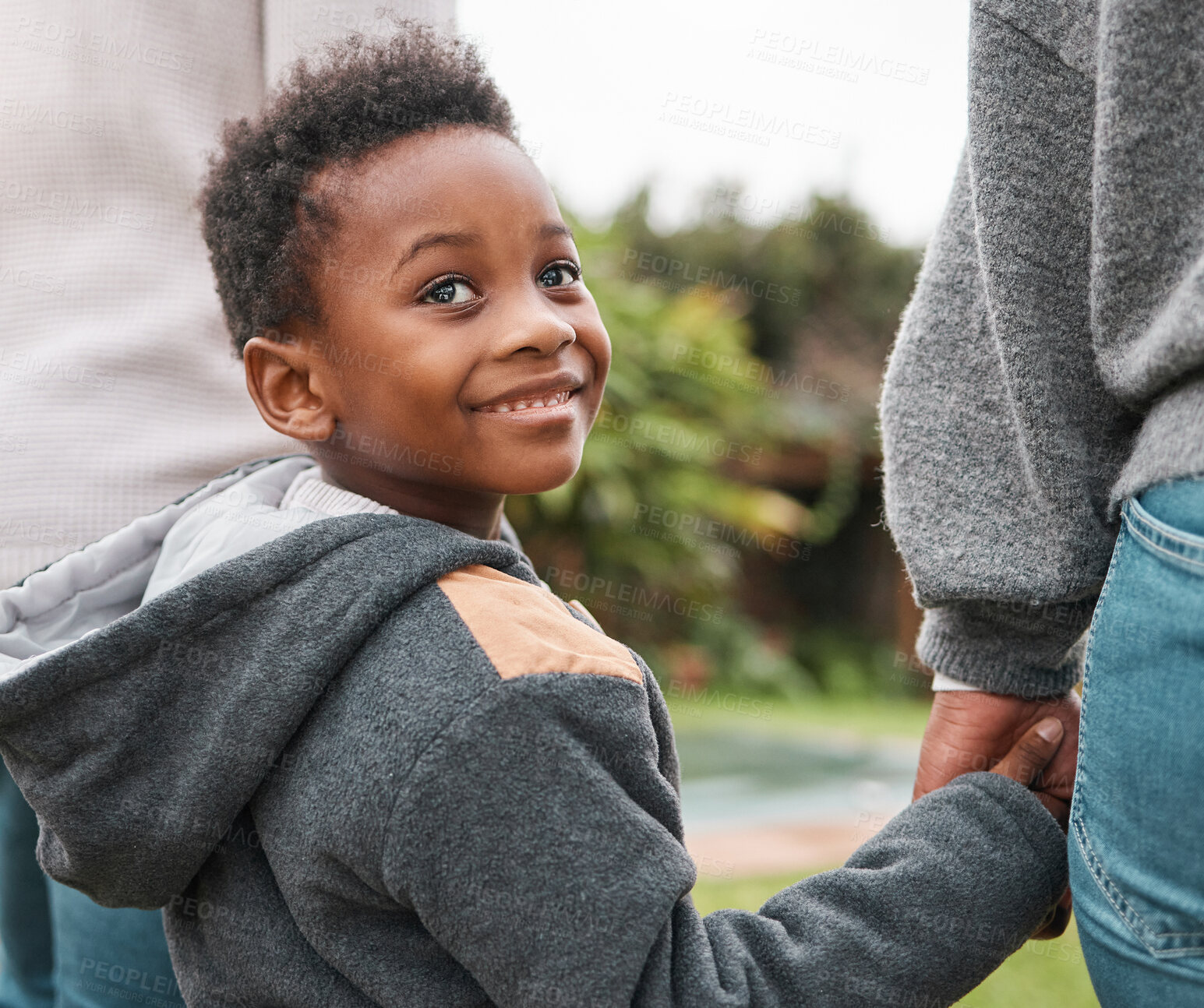 Buy stock photo Shot of an adorable little boy holding his parents hands while walking together outdoors