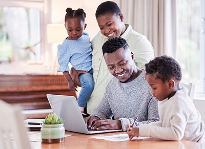 Buy stock photo Shot of a happy young family huddled together while looking at a laptop at home
