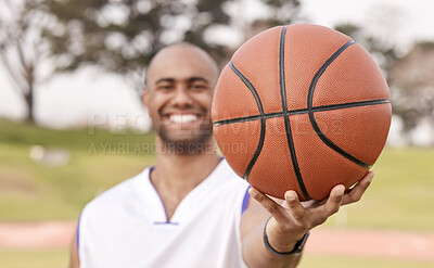 Buy stock photo Shot of an unrecognisable man standing alone outside and holding a basketball