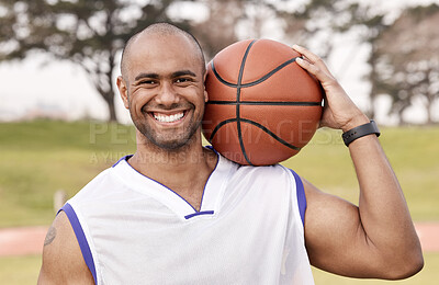 Buy stock photo Shot of a handsome young man standing alone outside and holding a basketball