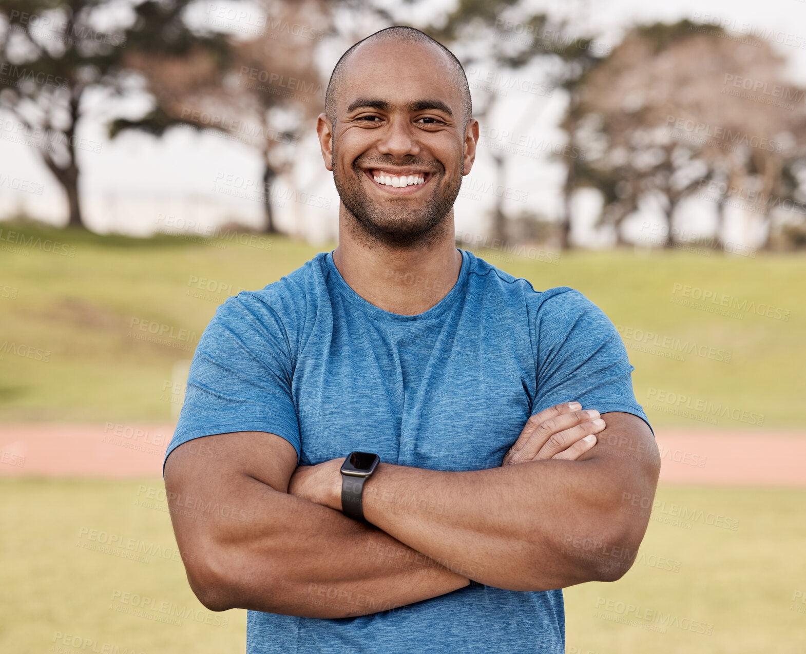 Buy stock photo Shot of a handsome young man standing alone outside with his arms folded before playing sports