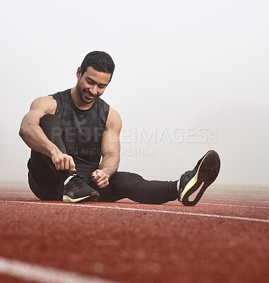 Buy stock photo Shot of a young male athlete tying his shoe laces before a race