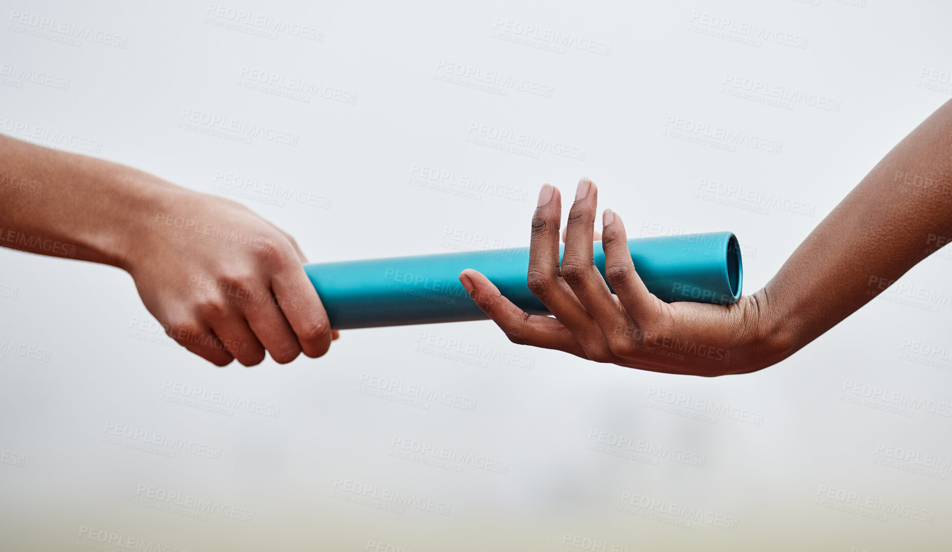 Buy stock photo Shot of two athletes passing a baton during a relay race