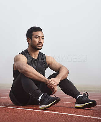 Buy stock photo Shot of a young male athlete sitting on the track before a race