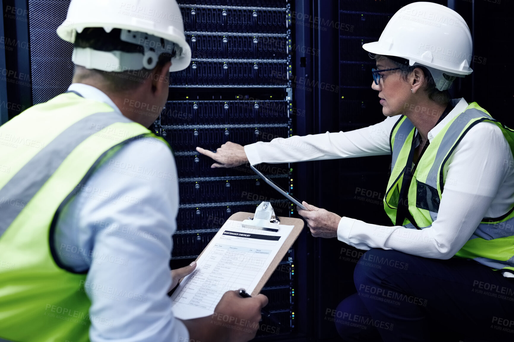 Buy stock photo Shot of two technicians working together in a server room