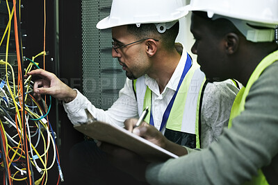 Buy stock photo Shot of two technicians working together in a sever room