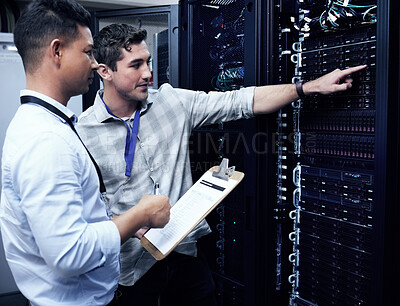Buy stock photo Shot of two technicians working together in a sever room