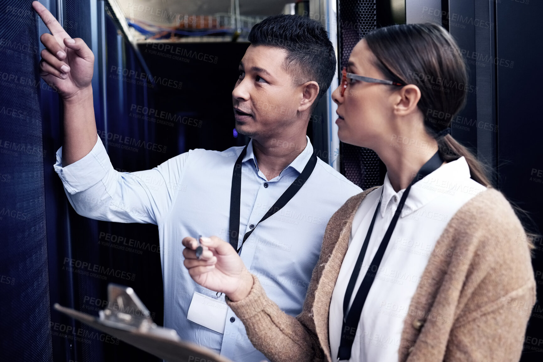 Buy stock photo Shot of two technicians working together in a sever room