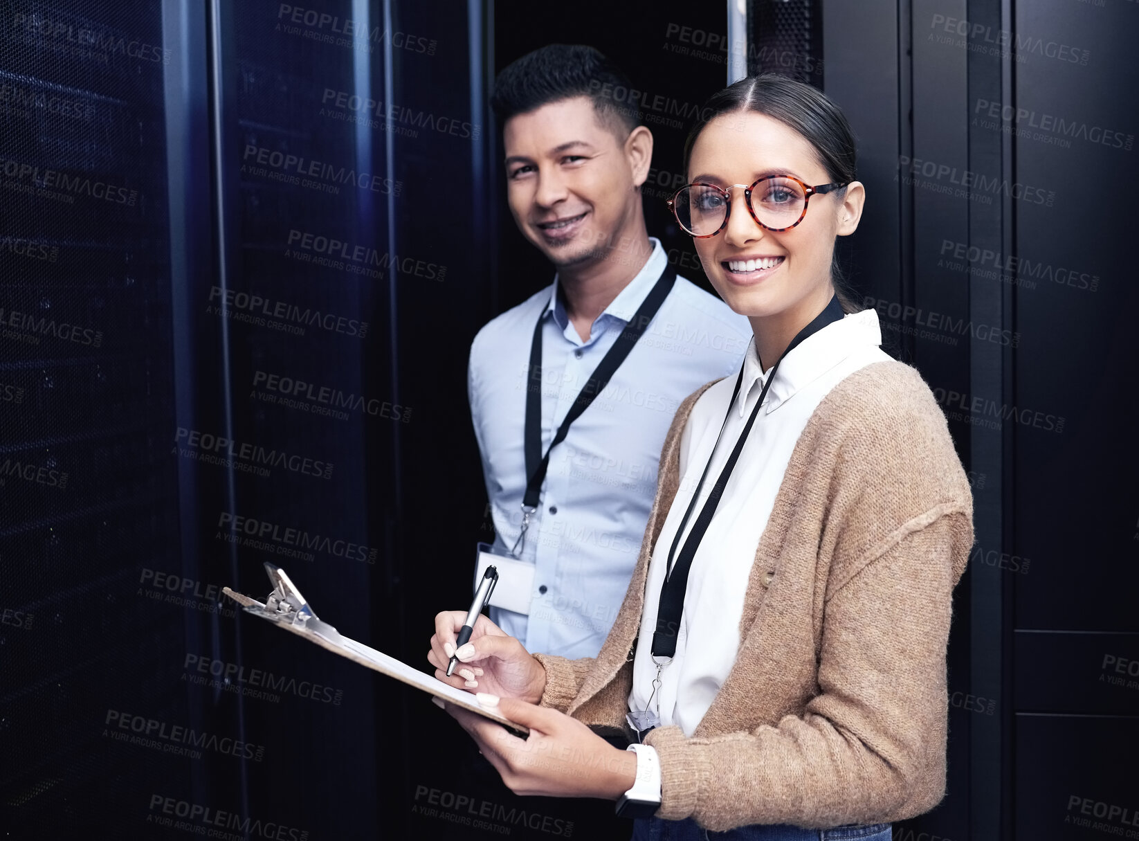 Buy stock photo Shot of two technicians working together in a server room