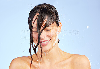 Buy stock photo Shot of a young woman washing her hair in the shower against a blue background