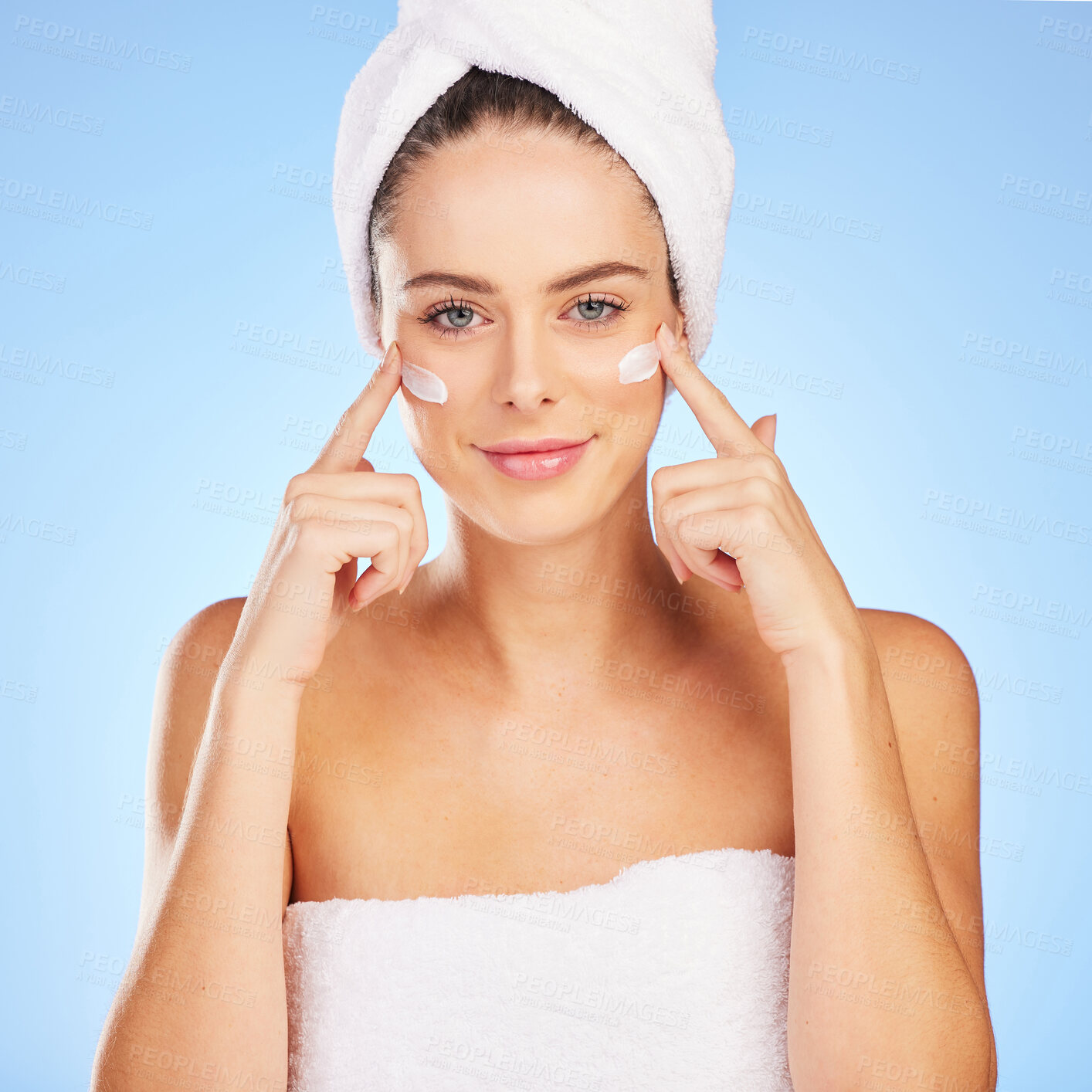 Buy stock photo Shot of a young woman doing her skincare routine against a blue background