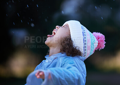 Buy stock photo Shot of an adorable little girl standing alone outside and playing in the rain