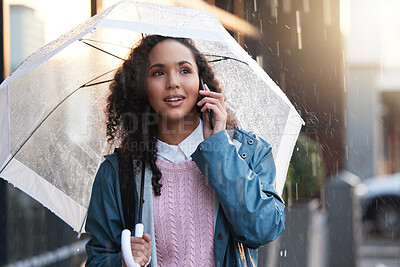 Buy stock photo Shot of a young woman on a call while holding an umbrella in the city