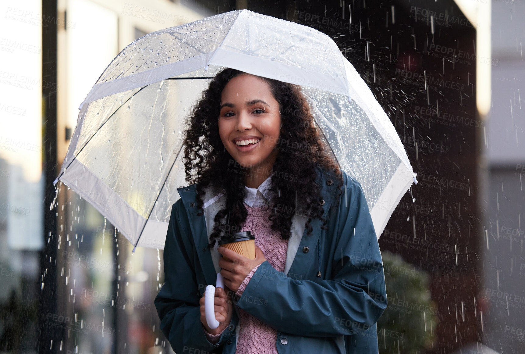 Buy stock photo Shot of a young woman holding an umbrella and coffee cup in the city