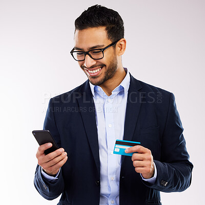 Buy stock photo Shot of a handsome businessman standing against a grey studio background and using his cellphone for online shopping
