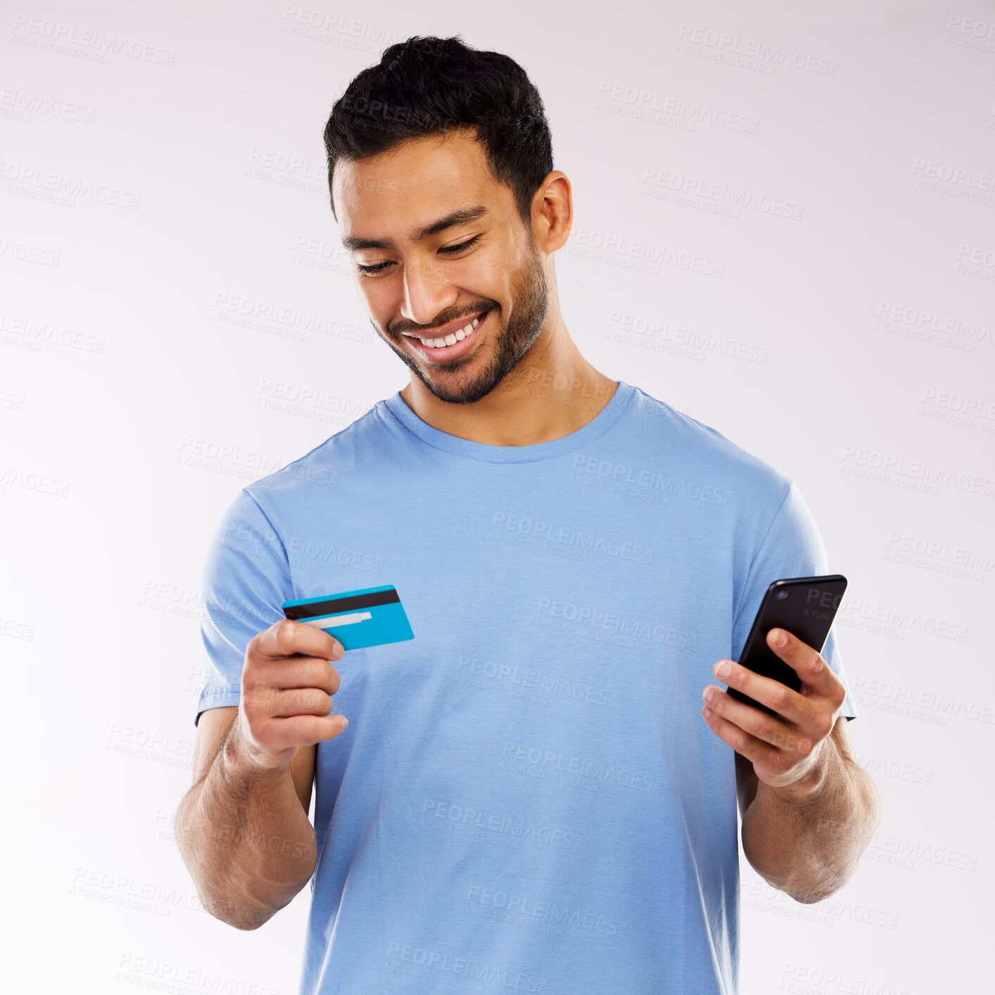 Buy stock photo Shot of a handsome man standing against a grey studio background and using his cellphone for online shopping