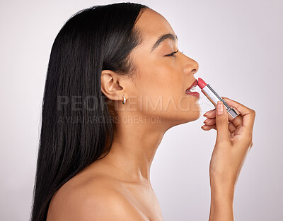 Buy stock photo Cropped shot of an attractive young woman applying lipstick against a pink background