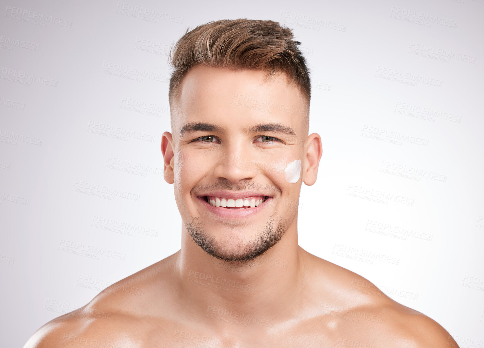 Buy stock photo Studio shot of a young man applying moisturizer to his face against a grey background