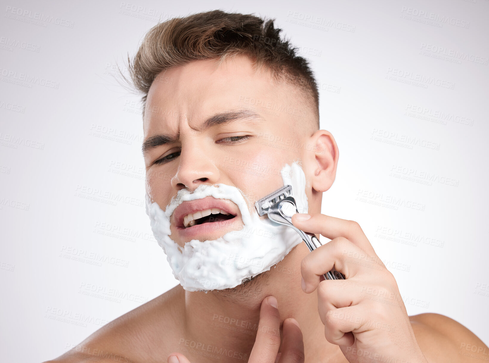 Buy stock photo Man, face and shaving foam with razor in studio, grooming and facial care for beard hair removal or painful tool. Hurt, skincare and dermatology or cosmetology, cleaning hygiene and white background