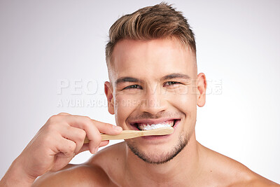 Buy stock photo Studio shot of a young man brushing his teeth against a grey background