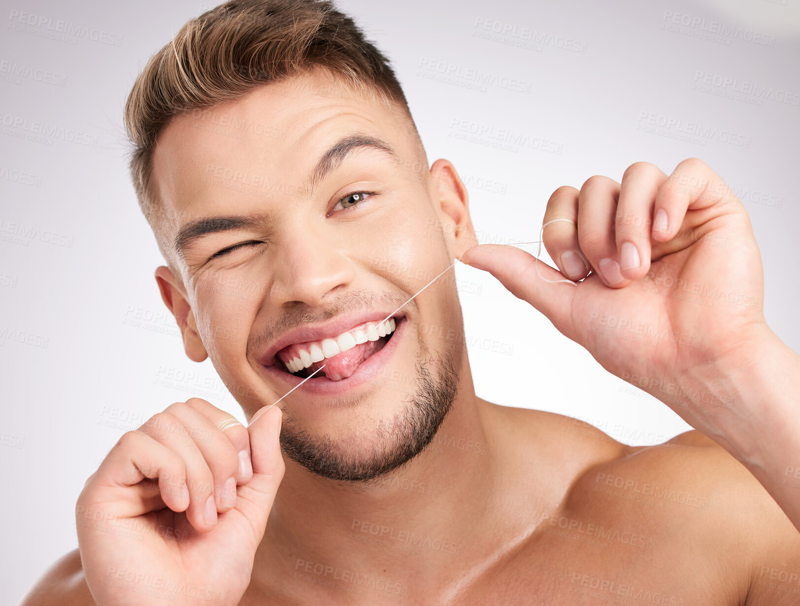 Buy stock photo Studio shot of a young man flossing his teeth against a grey background