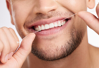 Buy stock photo Closeup, man and flossing teeth for hygiene with wellness, mouth care and gum health for fresh breath in studio. Male person, dental string and cleaning tooth with oral benefits by white background