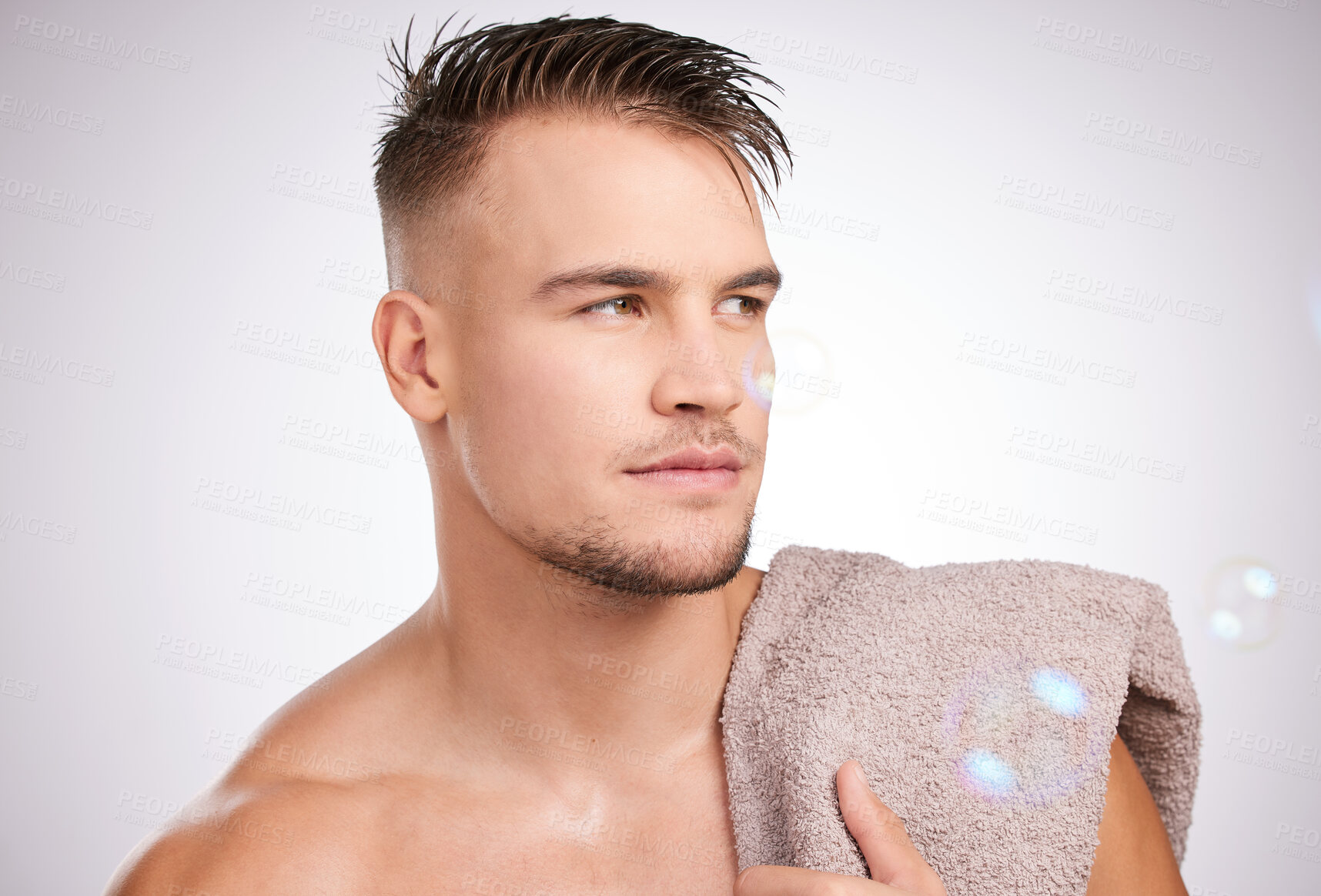 Buy stock photo Shot of a young man holding a towel against a grey background