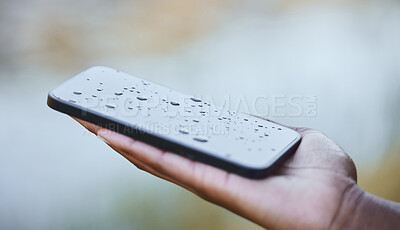 Buy stock photo Shot of a woman holding a wet phone during a camping trip