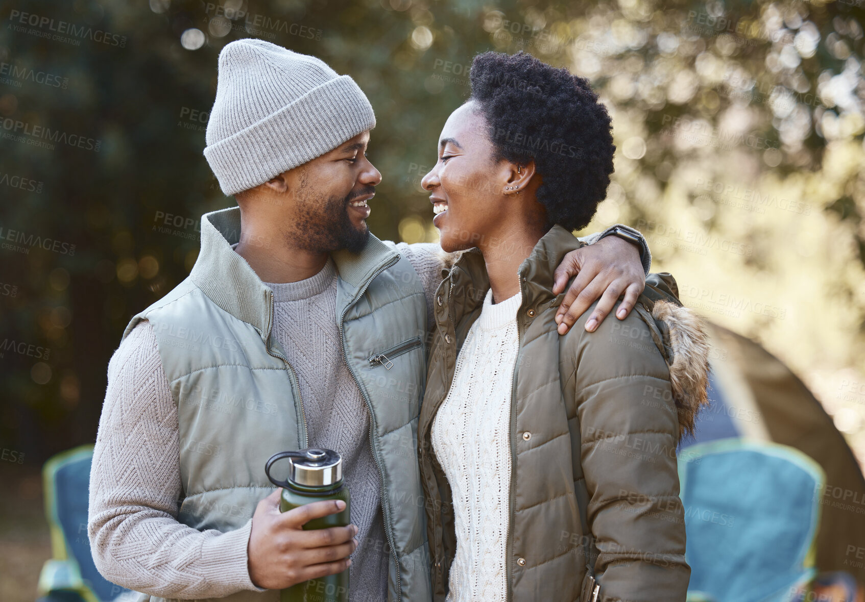 Buy stock photo Shot of a young couple being loving while camping together