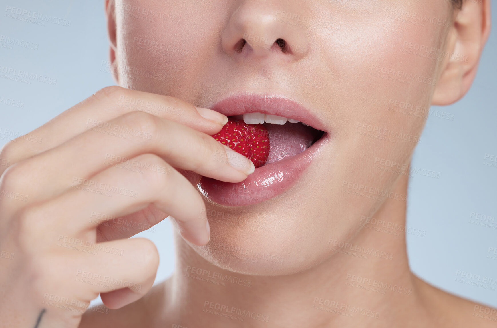 Buy stock photo Studio shot of an unrecognizable young woman biting into a strawberry against a grey background