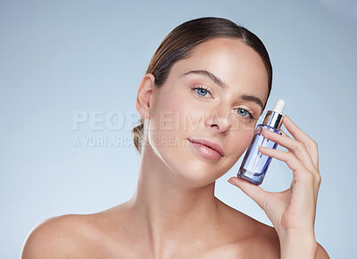 Buy stock photo Portrait, skincare and woman with beauty serum in studio, hand and product for glow and vitamin c. Dermatology, shine and bottle for aesthetic, hyaluronic acid and girl in blue background of spa