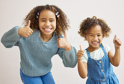 Buy stock photo Shot of two adorable little girls standing together and showing a thumbs up