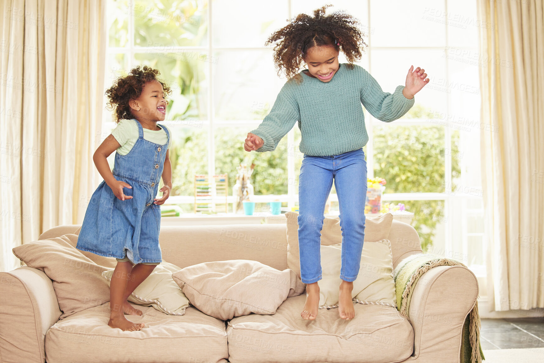 Buy stock photo Children, girls and jumping on sofa in home, bonding and game for having fun or love in childhood. Sisters, kids and playing together on couch in living room, happiness and weekend for support