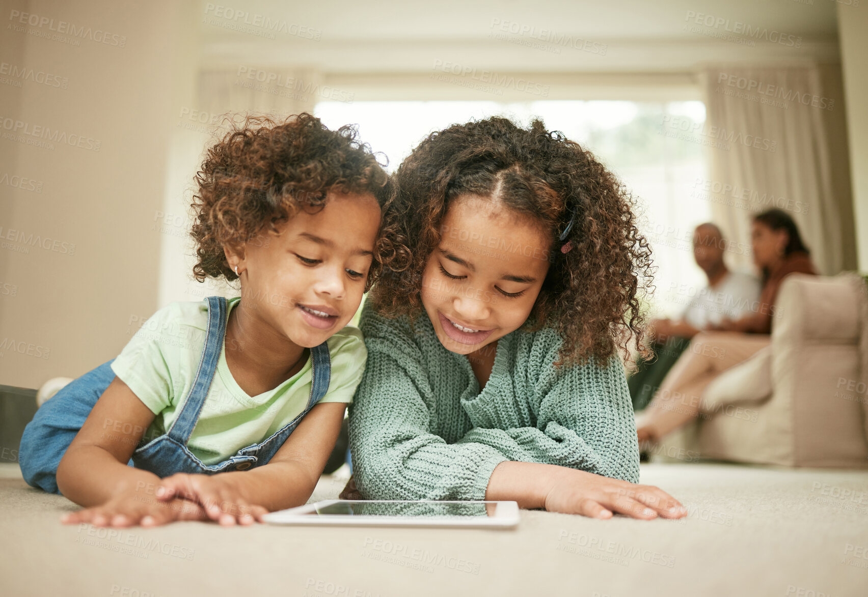 Buy stock photo Shot of two sisters using a digital tablet at home