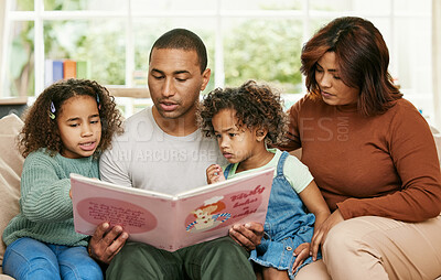 Buy stock photo Shot of a young family reading a book at home
