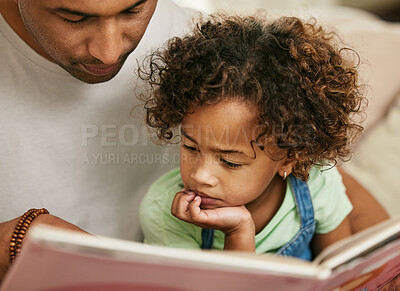Buy stock photo Shot of a young father reading a book with his daughter at home
