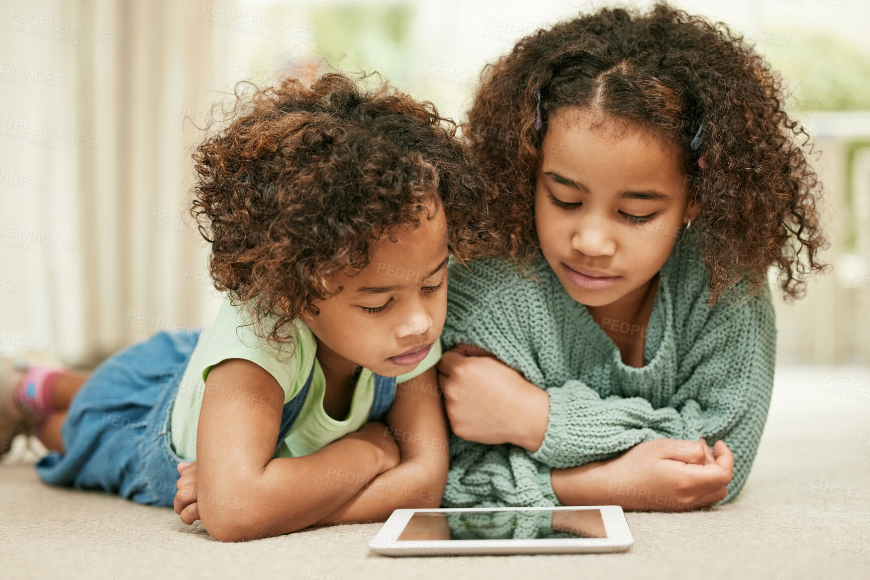 Buy stock photo Shot of two sisters using a digital tablet at home