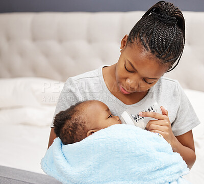 Buy stock photo Shot of a woman bottle feeding her baby at home