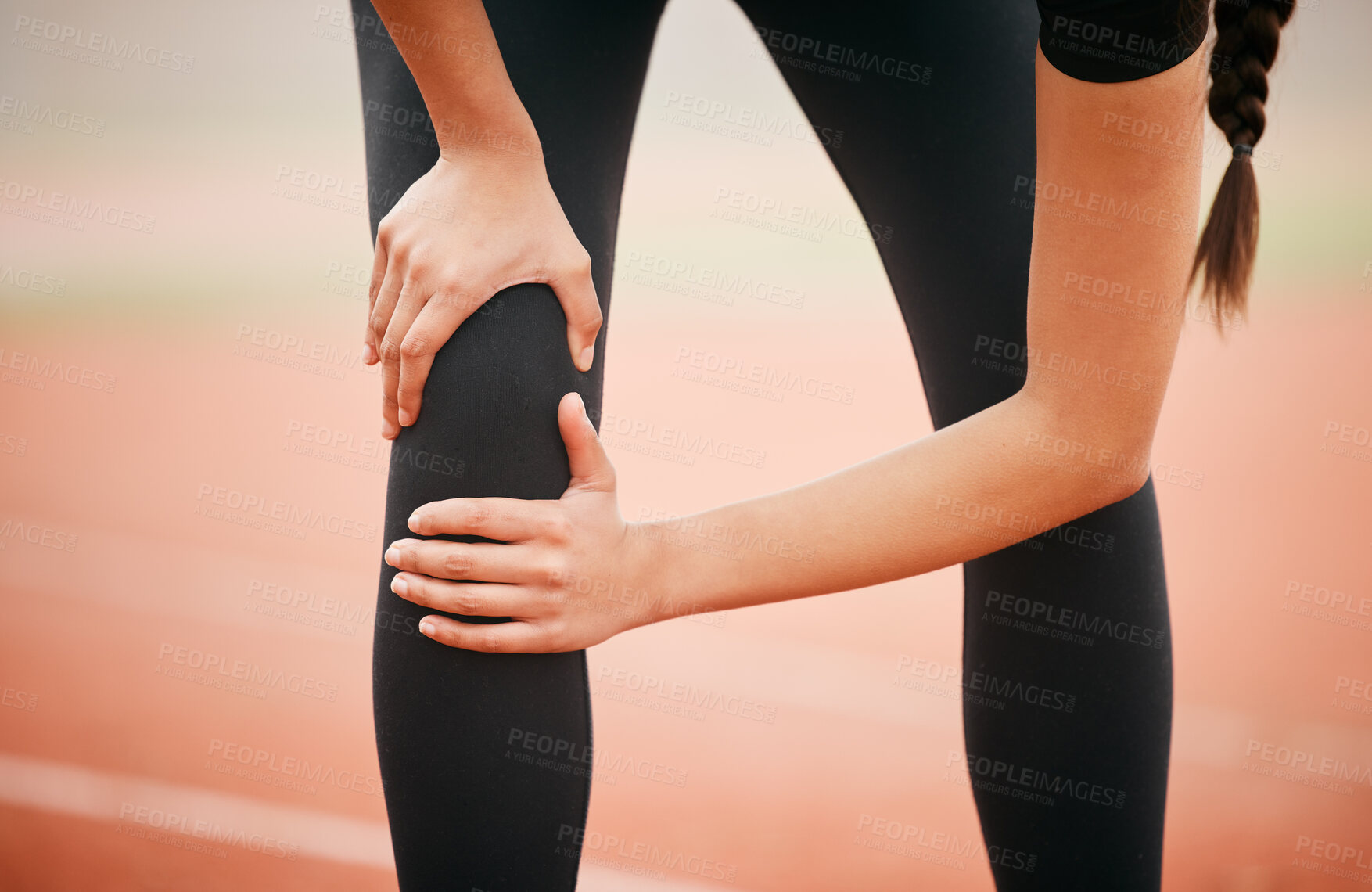 Buy stock photo Shot of an athletic young woman suffering from a sports injury while out on the track