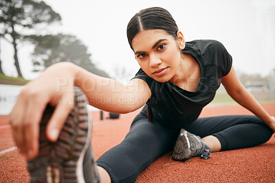 Buy stock photo Shot of an athletic young woman stretching while out on the track