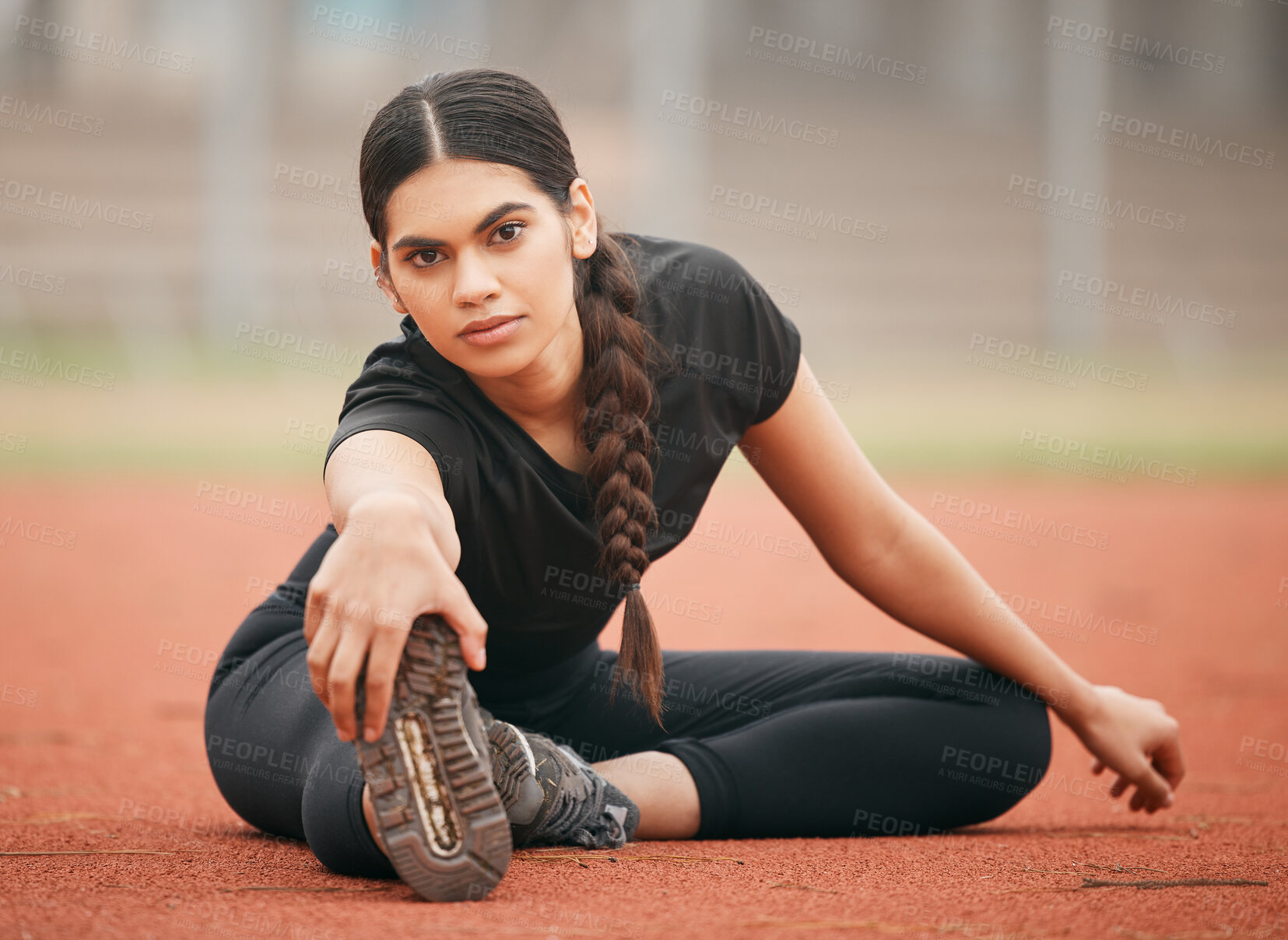 Buy stock photo Shot of an athletic young woman stretching while out on the track