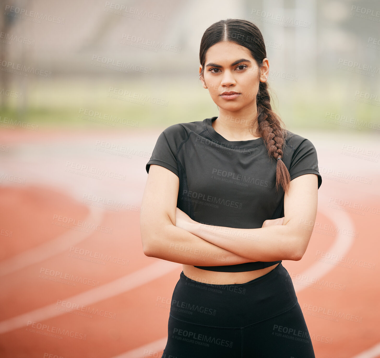 Buy stock photo Shot of an athletic young woman standing with her arms crossed on the track
