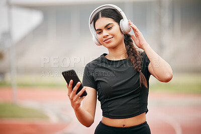 Buy stock photo Shot of an athletic young woman holding her cellphone while listening to music through her headphones