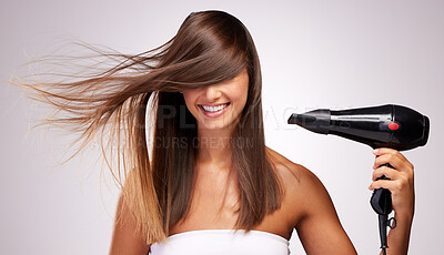Buy stock photo Studio shot of an attractive young woman blowdrying her hair against a grey background