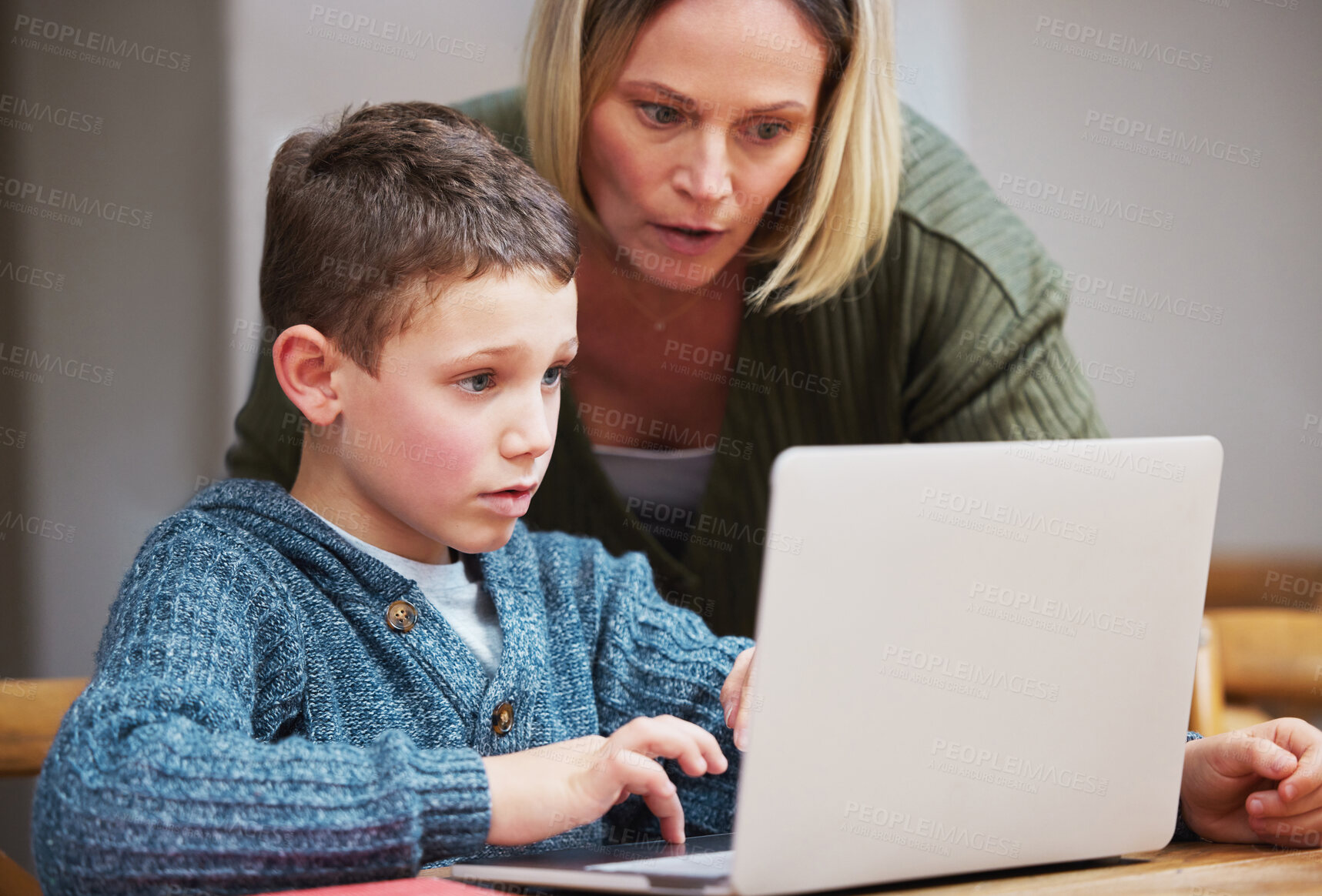 Buy stock photo Shot of a mother helping her son complete his homework using a laptop