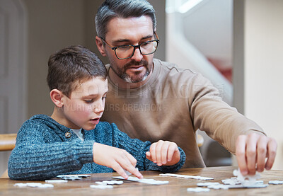 Buy stock photo Shot of a father and son completing a puzzle together